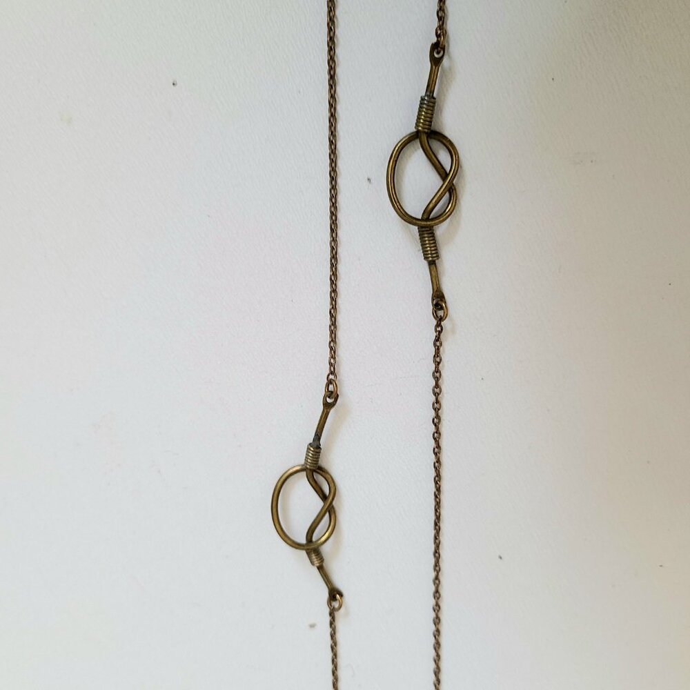 Brass long chain with knot details.